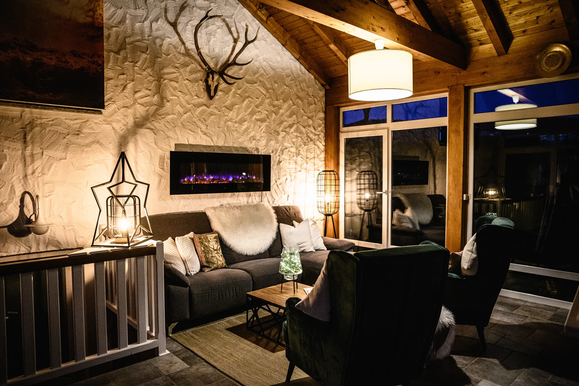 Der Wintergarten von innen am Abend mit warmem Licht, Sofa und Sesseln