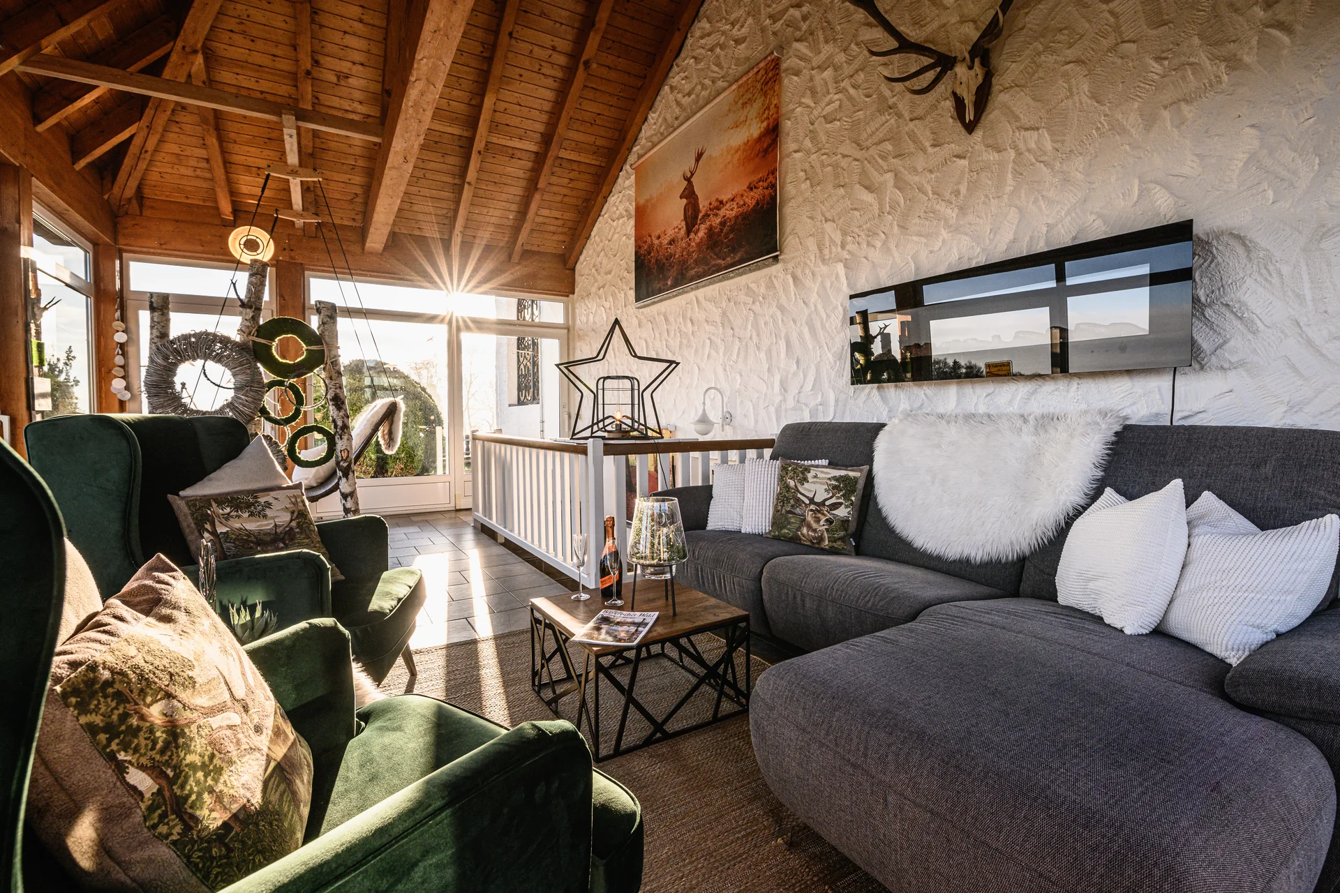 Sofa und Sessel unter dem hohen Holzdach des Wintergartens